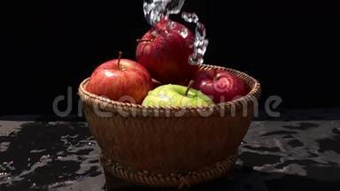 把水浇在红色和绿色的苹果上，用竹篮子浇在黑色的背景上